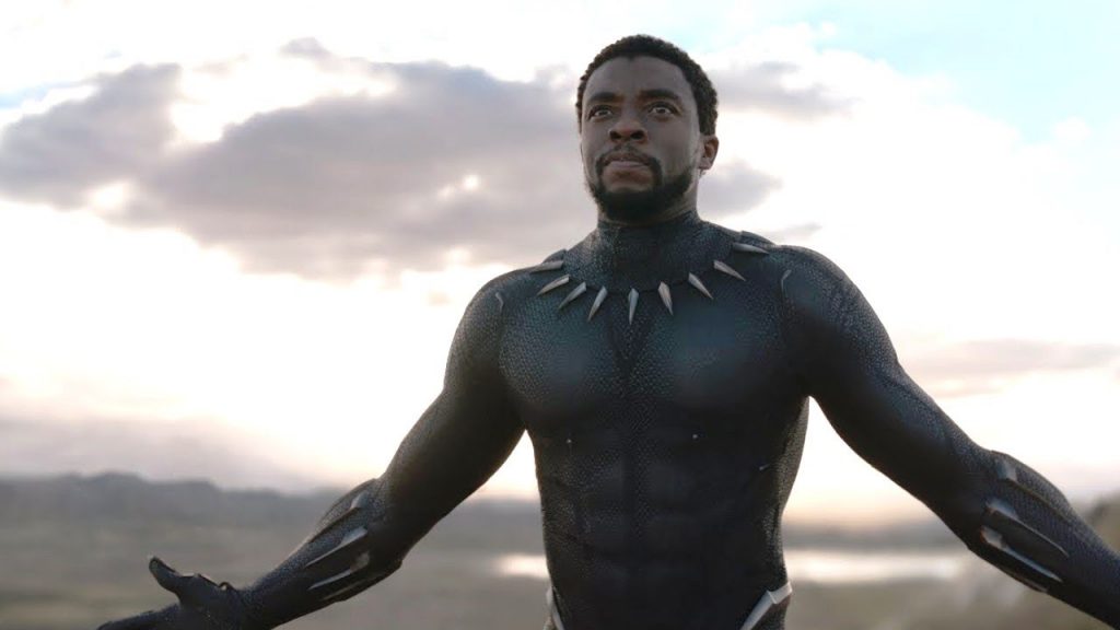 black panther stands with his hands out. he doesn't wear his mask