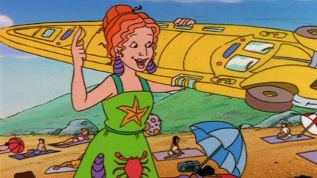 Professor Frizzle (as Ms. Frizzle) at the beach with the Magic School Bus transformed into a surfboard.