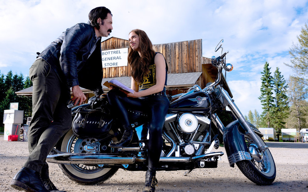 Doc staring lovingly at Wynonna while Wynonna sits on a motorcycle outside a rest stop.