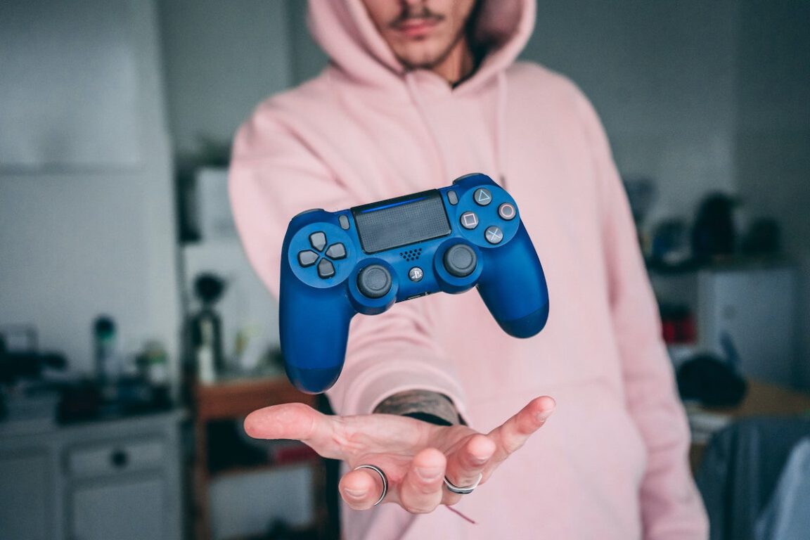 a man in a pink hoodie holding a video game controller