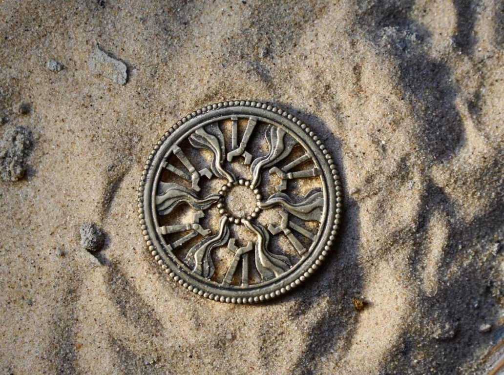 A round dull gold emblem which is the guild badge from lord of the rings: rings of power