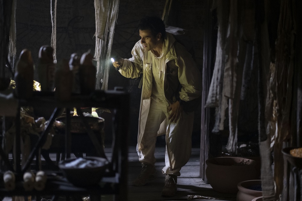 Oscar Isaac as Steven, looking through the contents inside a pyramid with a flashlight on Moon Knight Season 1 Episode 4 "The Tomb."