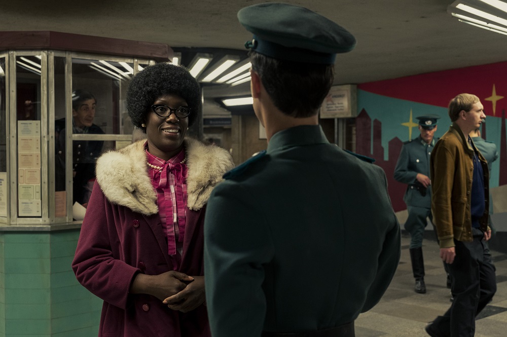 Carolyn Michelle Smith as Agnes, standing in front of a police officer in a maroon fur coat on Russian Doll Season 2 Episode 6 "Schrödinger's Ruth."