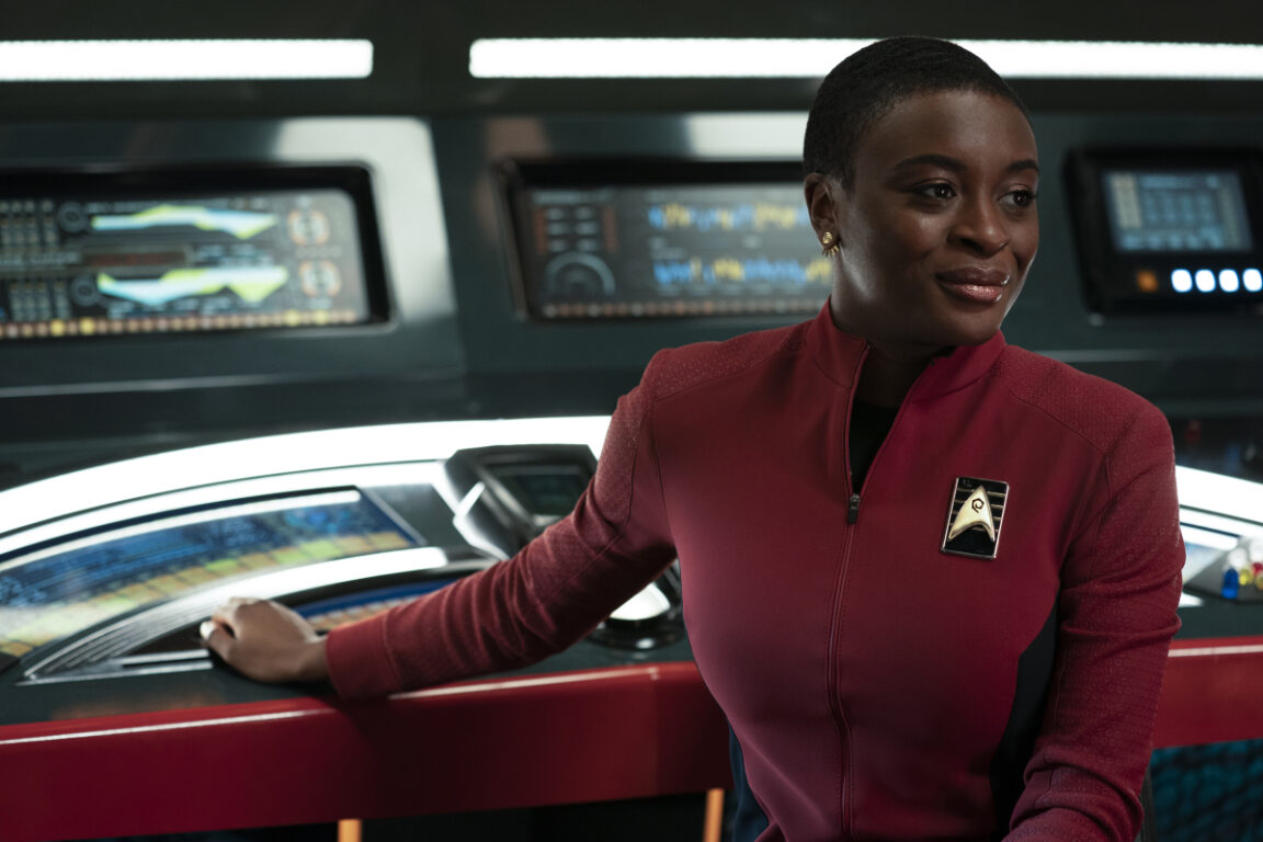 Celia Rose Gooding as Uhura, Enterprise Comm Officer, sitting and looking at something off camera.