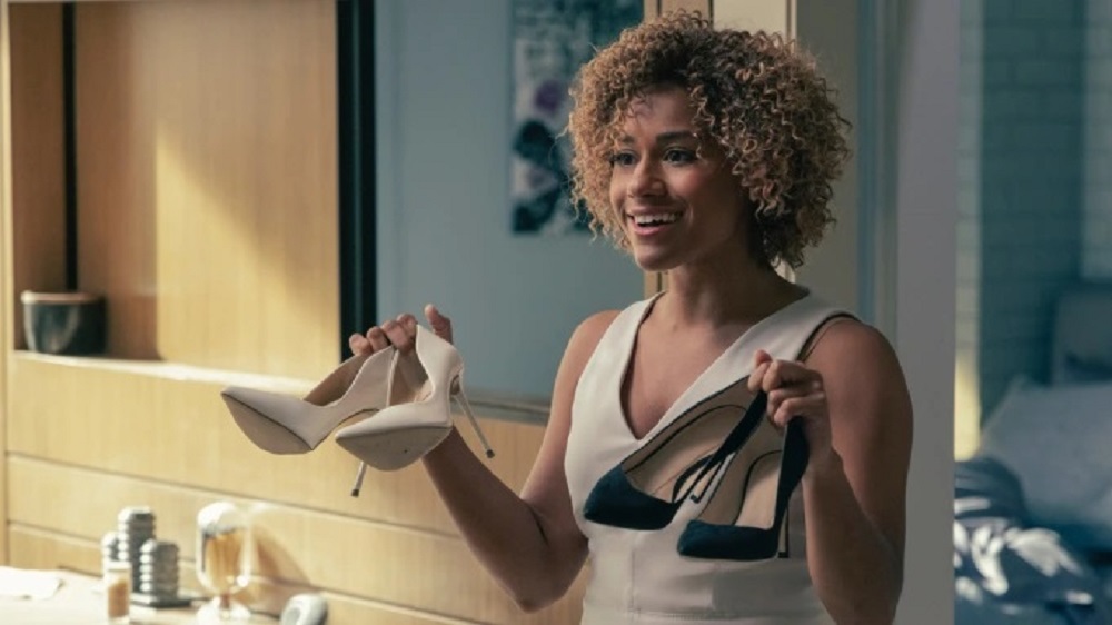 Ariana DeBose holding a pair of white heels in one hand and a pair of black heels in the other hand in Westworld Season 4.