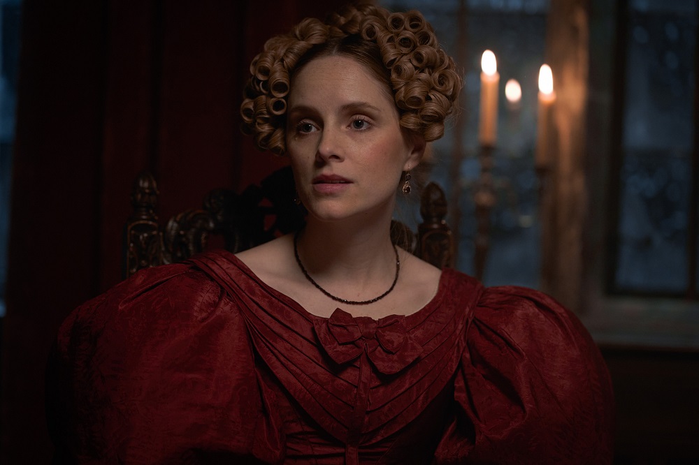Ann Walker wearing a red dress and sitting at a dinner table in Gentleman Jack Season 2 Episode 2 "Two Jacks Don't Suit."