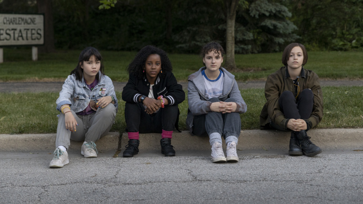 Tiaffny, Erin, Mac and KJ sitting on a curb in Paper Girls.
