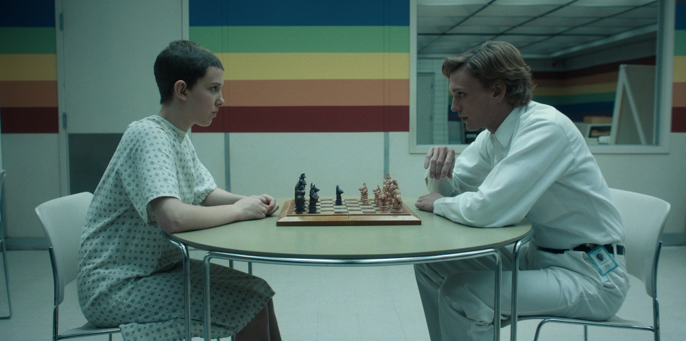 El and Peter sitting across from one another in the Rainbow Room playing chess while he explains to her his plan.