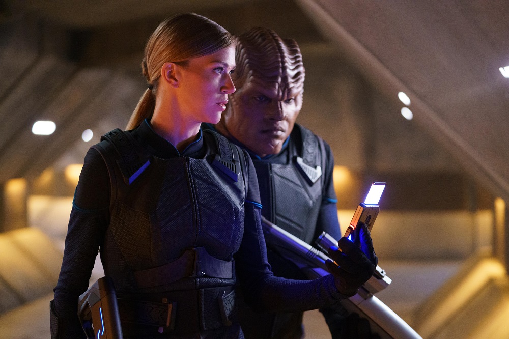 Cmdr. Kelly Grayson and Lt. Cmdr. Bortus stand in tactical gear in a dimly lit tunnel on The Orville: New Horizons Season 3 Episode 8 "Midnight Blue."