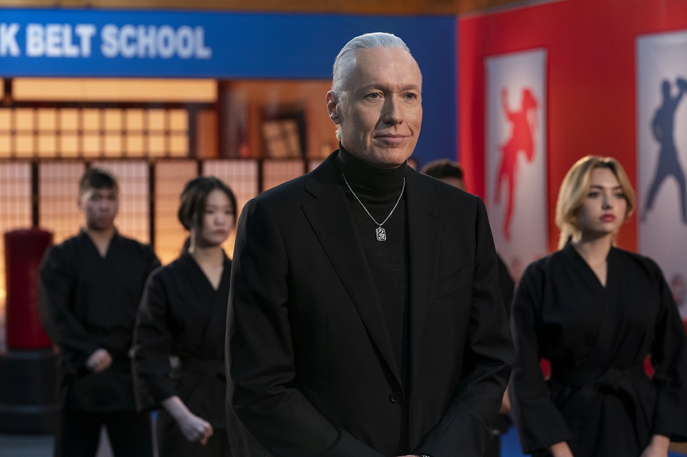 Terry Silver stands at attention, wearing all black while his students stand behind him on Netflix's Cobra Kai Season 5.
