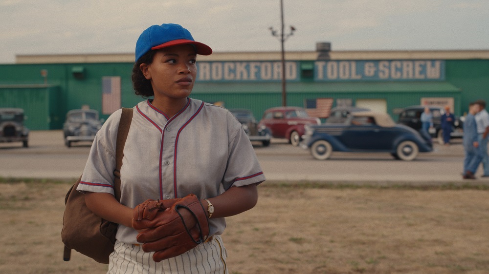 Max Chapman standing in front of the Rockford Tool & Screw Factory while wearing a baseball uniform on A League of Their Own Season 1 Episode 8 "Perfect Game."