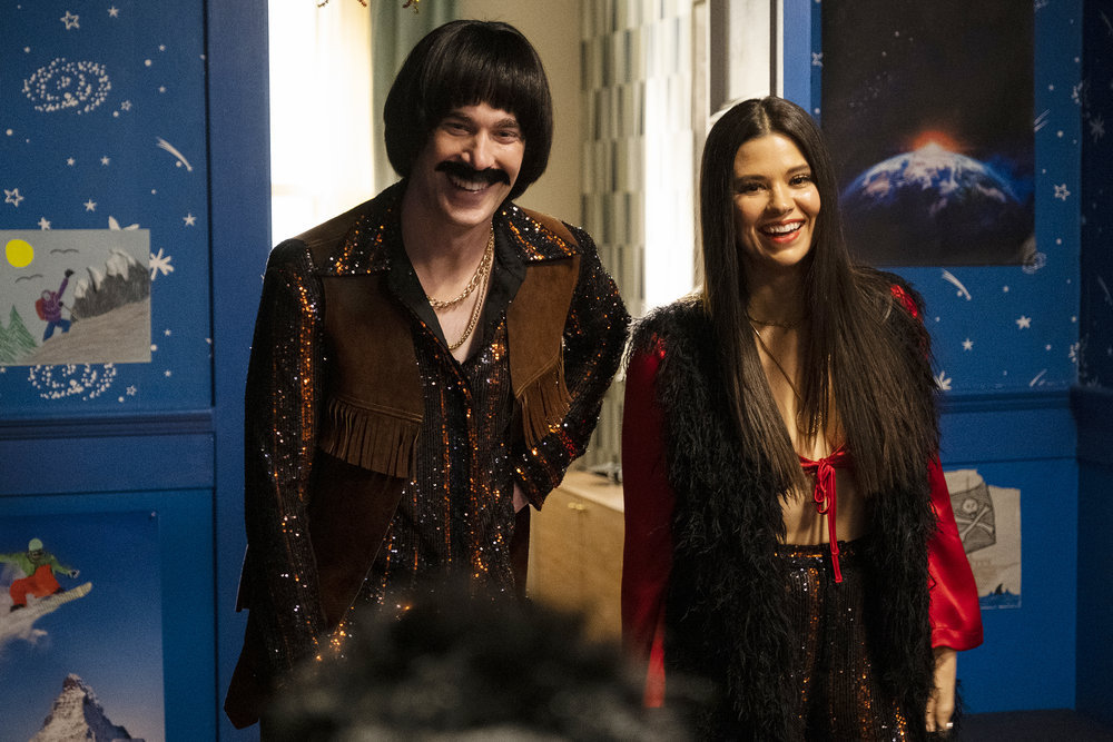Ben is wearing a Sonny Bono costume while Kate dons a Cher costume on Resident Alien Season 2 Episode 12, "The Alien Within."