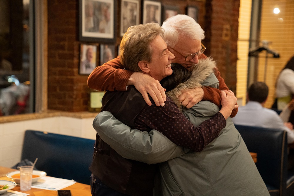 Charles, Oliver and Mabel embrace in a diner on Only Murders in the Building Season 2 Episode 7, "Flipping the Pieces."