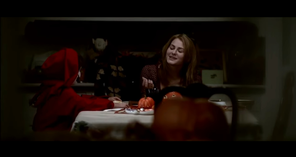 Laurie (Scout Taylor Compton) sits at a table with Tommy in the dark in Rob Zombie's Halloween. 