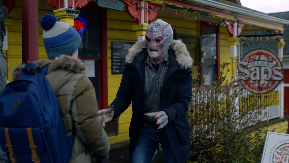 Alien Harry talks to Max outside while wearing a blue winter coat in Resident Alien Season 2 Episode 16, "I Believe in Aliens."