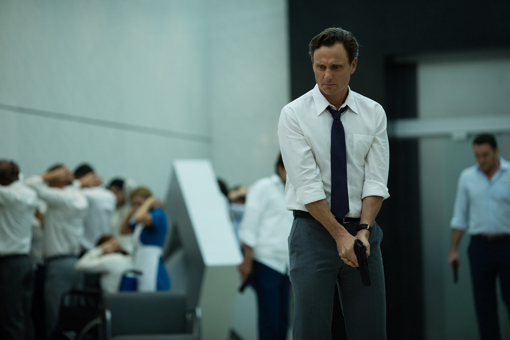 Barry wields a gun in a crowded room in The Belko Experiment.