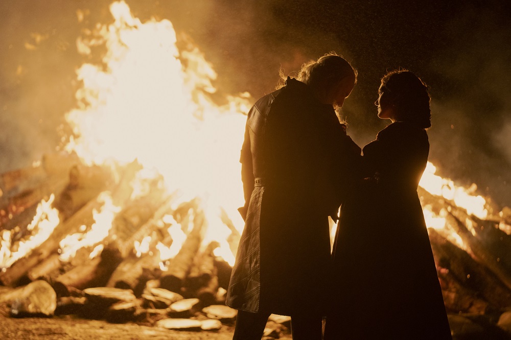 Viserys and Alicent stand before a blazing fire while gazing at each other on House of the Dragon Season 1 Episode 3, "Second of His Name."