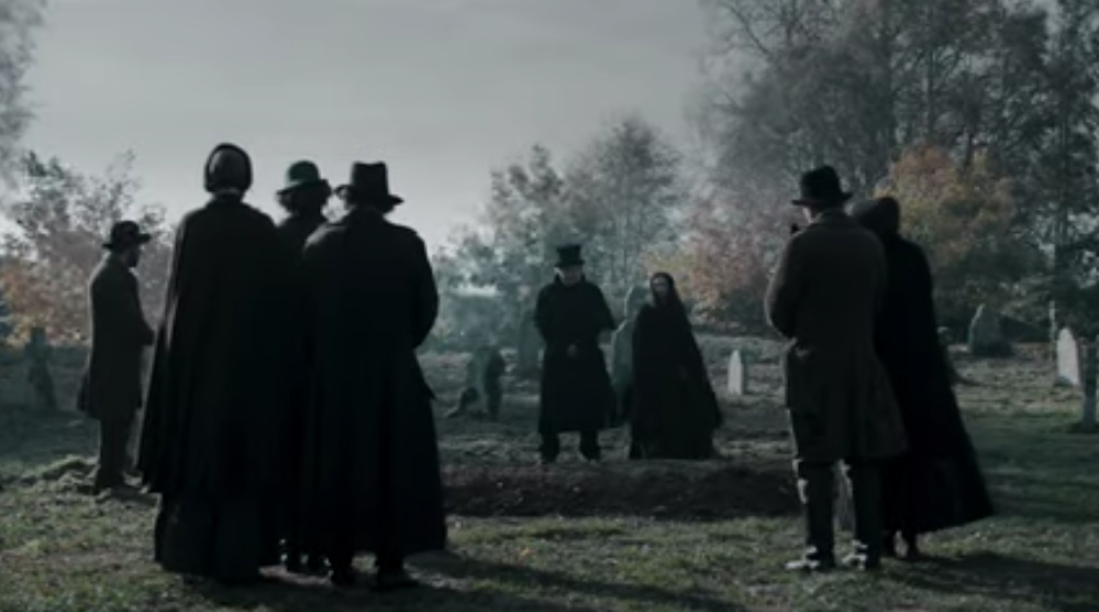 All of the characters in Raven's Hollow stand around an open grave for a funeral