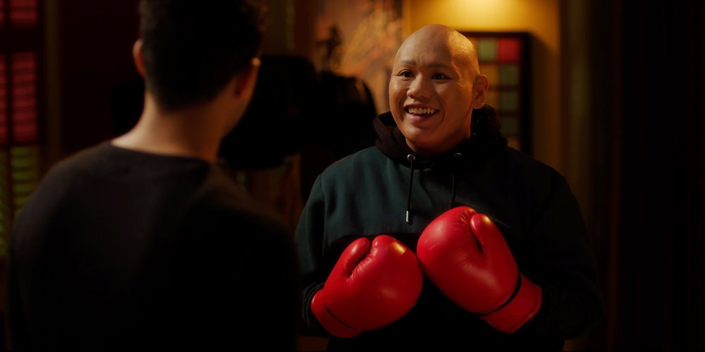 Reginald wears red boxing gloves while smiling at Maurice in his apartment in Reginald the Vampire Season 1 Episode 3, "Hypnos."