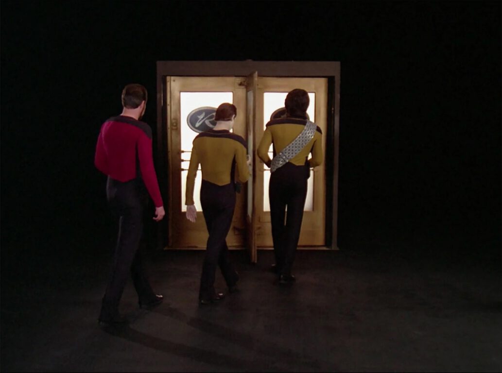 Riker (Jonathan Frakes), Data (Brent Spiner), and Worf (Michael Dorn) enter the doors of the Royale.