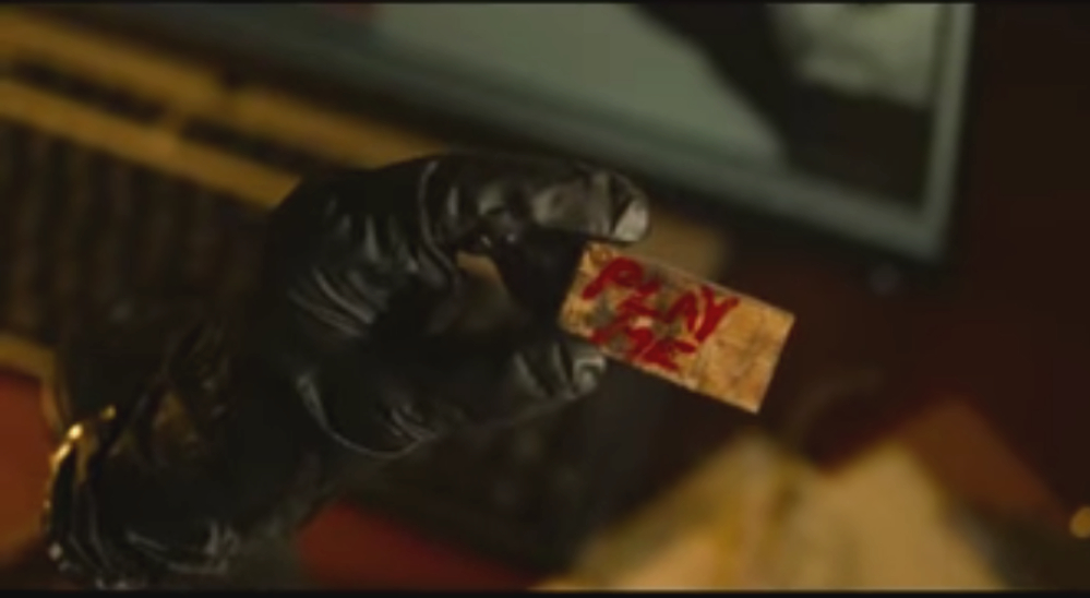 A detective holds a flash drive that says play me