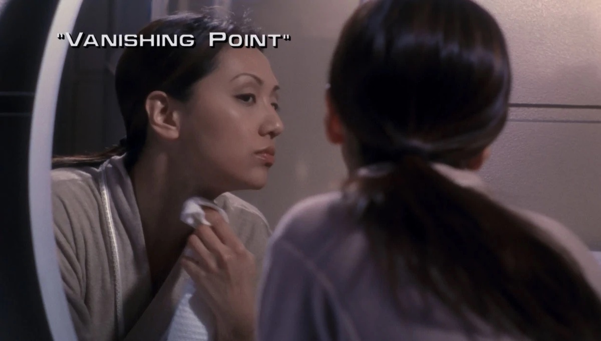 Hoshi Sato (Linda Park) looks at her reflection in the mirror in the title card for ENT season 2 episode 10, "Vanishing Point."