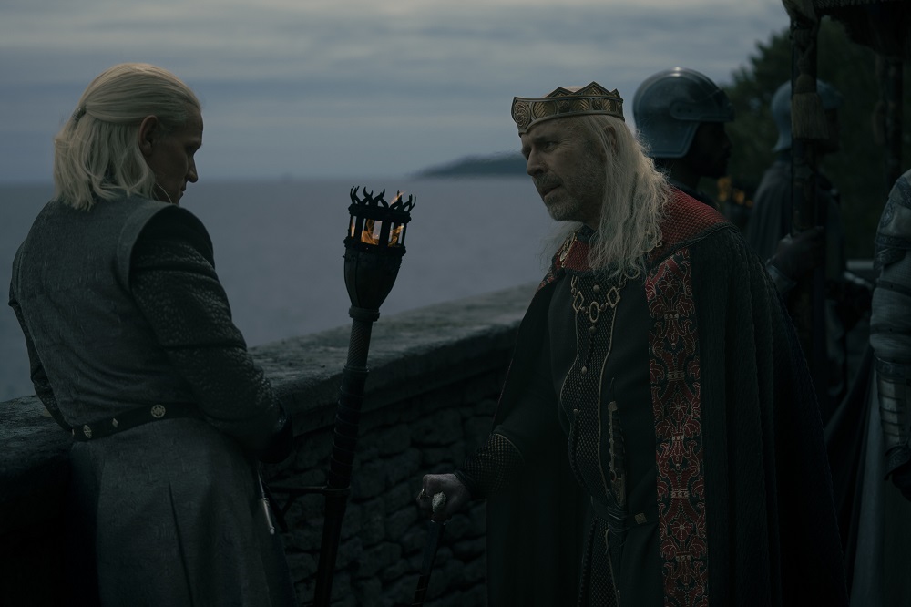 Daemon and King Viserys chat next to a stone wall overlooking the sea in House of the Dragon Season 1 Episode 7, "Driftmark."