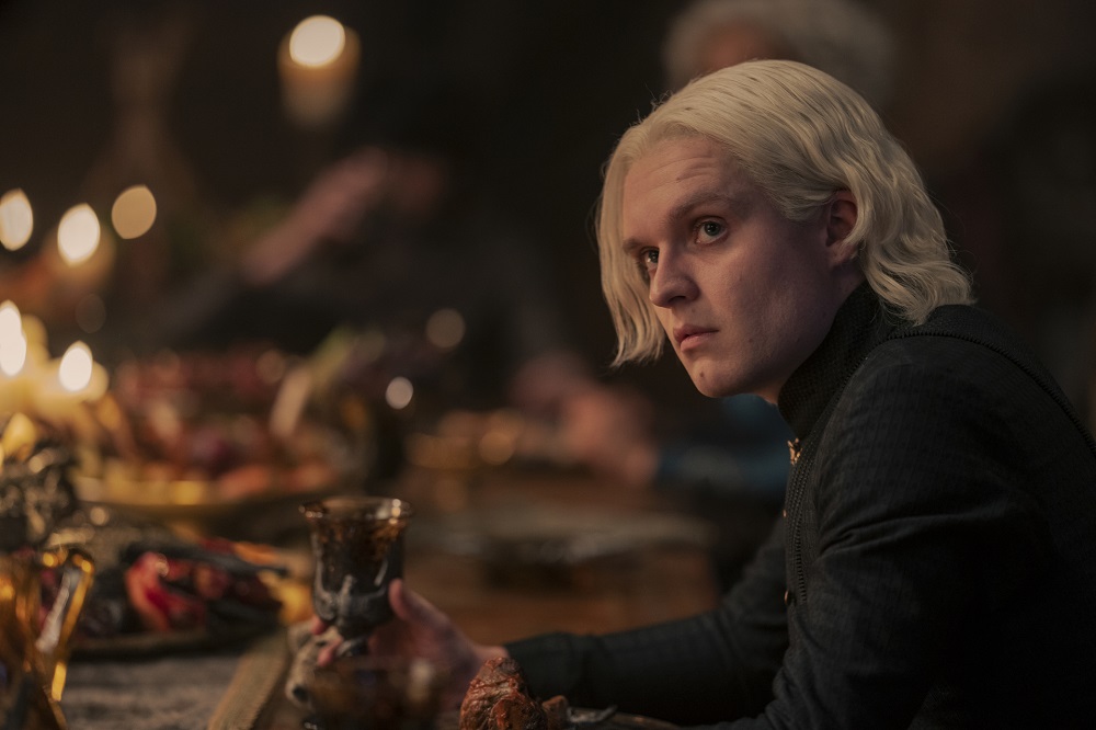 Aegon Targaryen sits at a table for dinner while looking suspiciously at something off screen in House of the Dragon Season 1 Episode 8, "The Lord of the Tides."