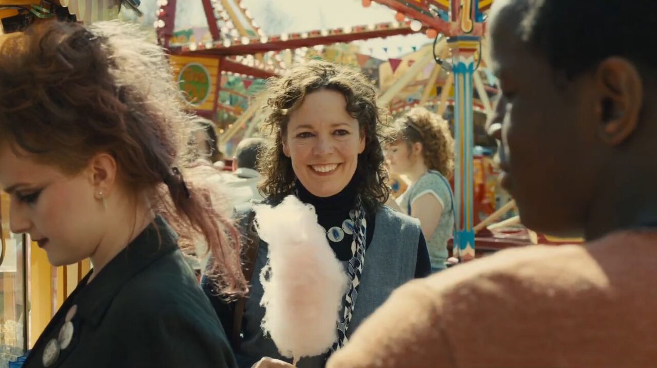 In Empire of Light, Olivia Colman smiles while eating cotton candy.
