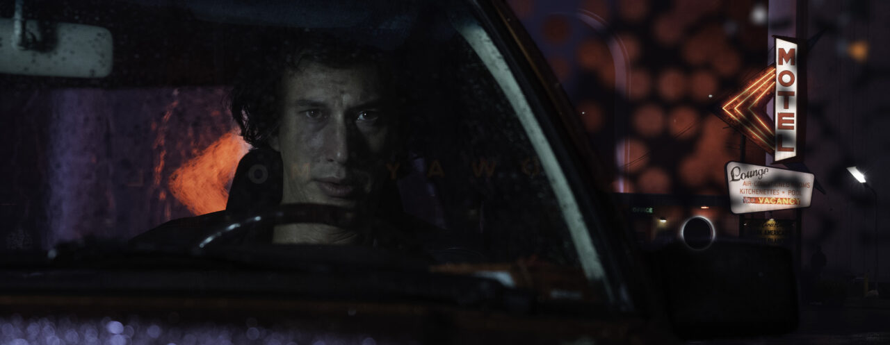 Adam Driver sits in his car in the dark in White Noise.