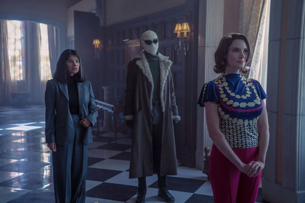 Dr. Harrison, Larry and Rita stand in the hallway of Doom Manor while looking pensive in Doom Patrol Season 4 Episode 1.
