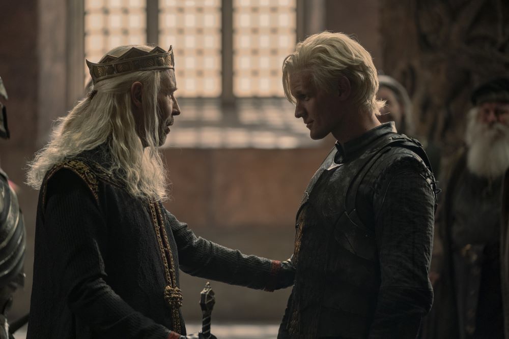 King Viserys and Daemon Targaryen stand in front of each other while smiling in the throne room in House of the Dragon Season 1 Episode 4, "King of the Narrow Sea."