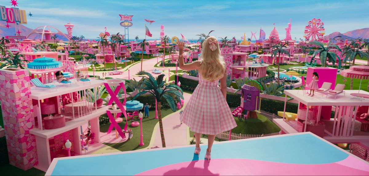 Barbie wears a light pink dress and heels with her back turned while looking out at Barbie Land.