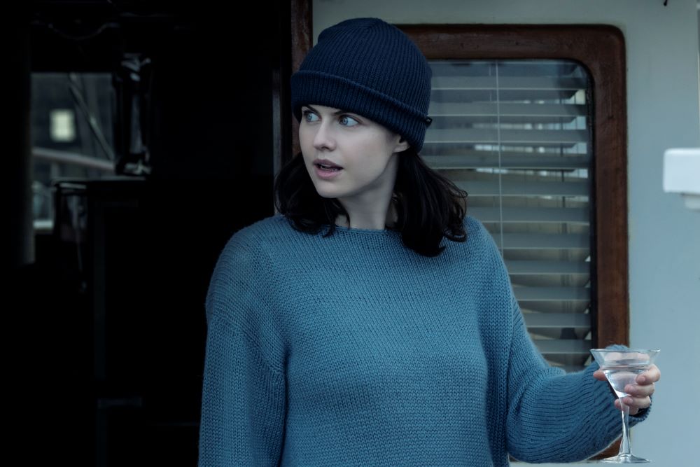 Rowan Fielding stands outside on a boat while wearing a blue cap and gray sweater in Mayfair Witches Season 1 Episode 1, "The Witching Hour."