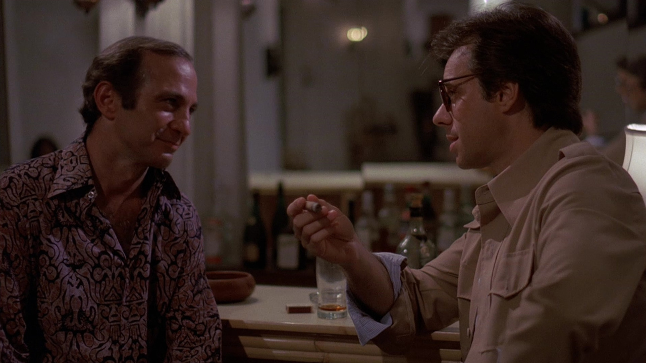 Ben Gazzara and Peter Bogdanovich talk at a restaurant table in Saint Jack.
