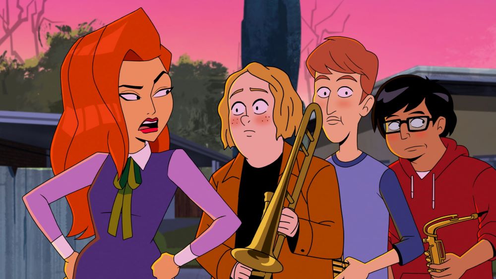 Daphne stands with her hands on her hips while looking irritated with three high school band students standing behind her in the TV show "Velma."