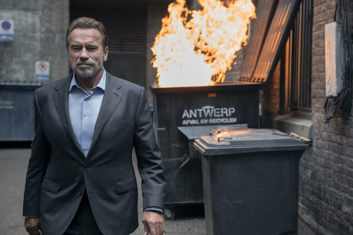 Arnold Schwarzenegger walks away from a dumpster on fire in FUBAR