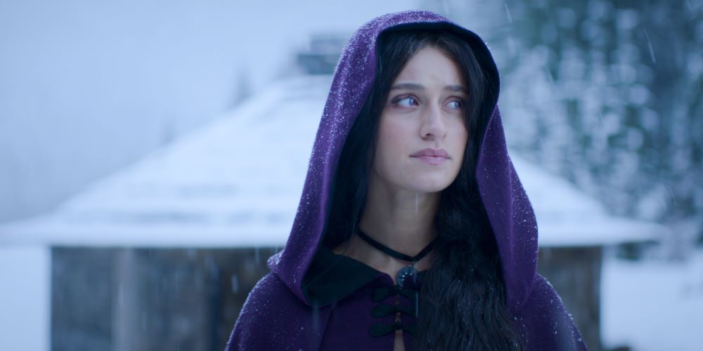 Yennefer wears a purple-hooded cloak while walking through the snow outside in The Witcher Season 3.