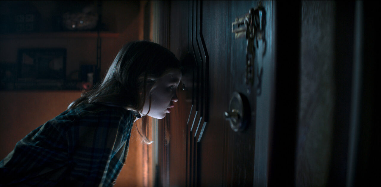 Nell Fisher as Kassie looking out the door in Evil Dead Rise