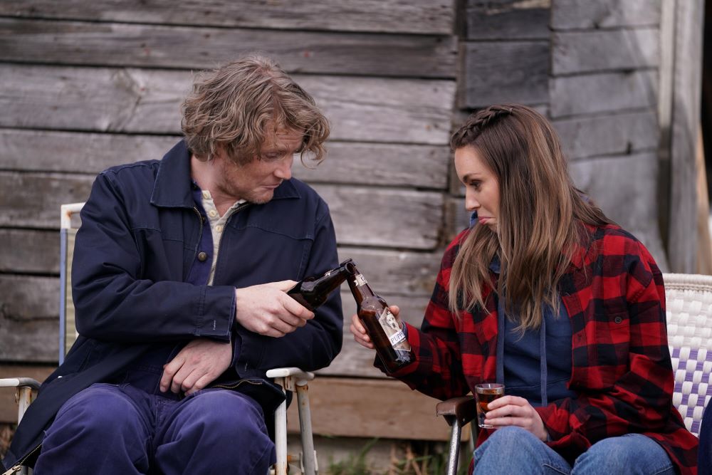 Daryl and Katy clink their beer bottles together in a toast while sitting outside in Letterkenny Season 11 Episode 7, "May 2-4."