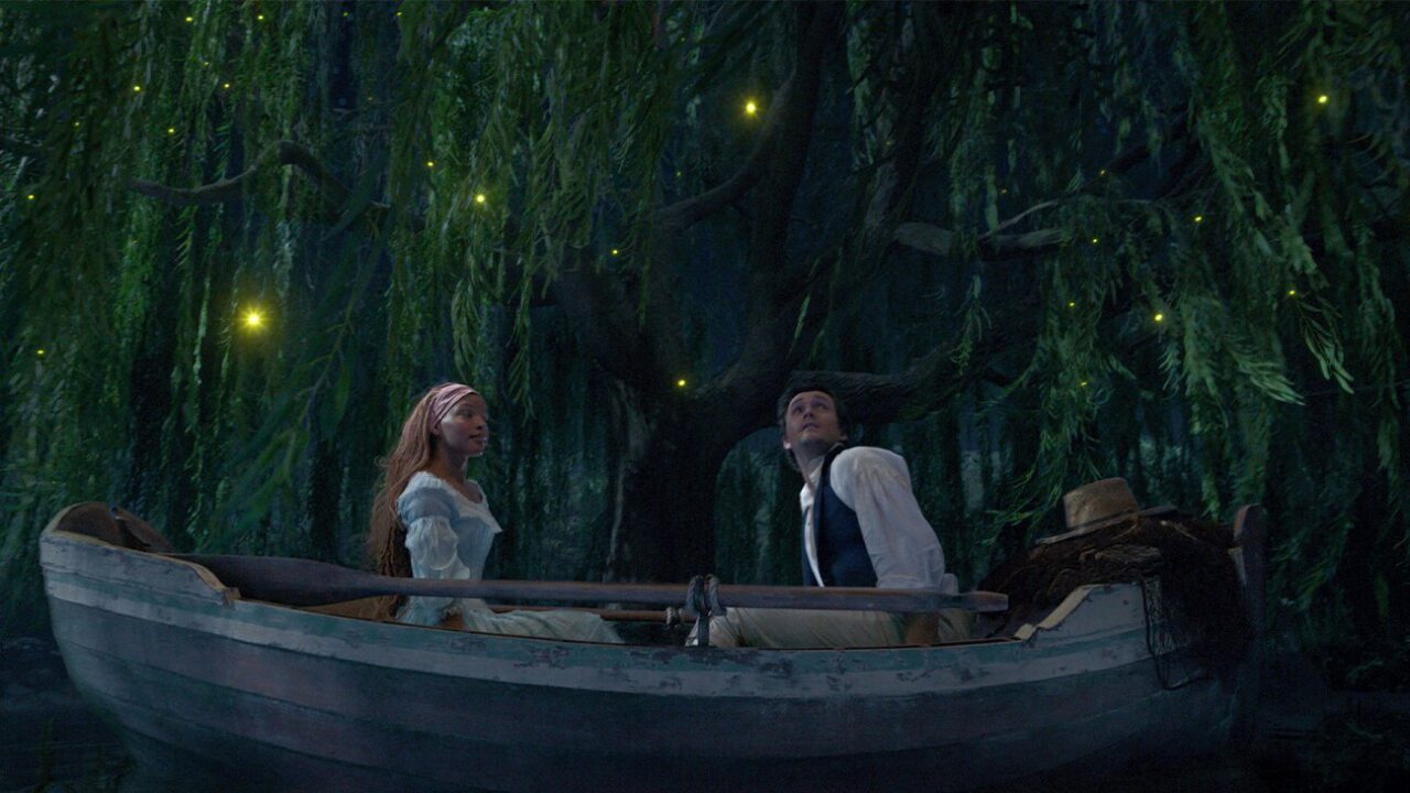 Halle Bailey and Jonah Hauer-King look longingly as they sit across from each other in a boat in The Little Mermaid.