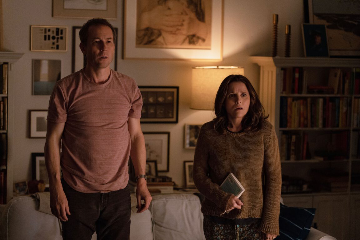 Tobias Menizes and Julia Louis-Dreyfus stare at the camera in bewilderment as they stand in their living room in You Hurt My Feelings. 