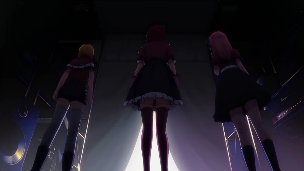 Ruby, Kana and MEM stand on a dark stage while preparing to perform in Oshi No Ko Season 1 Episode 11, "It's a Secret."