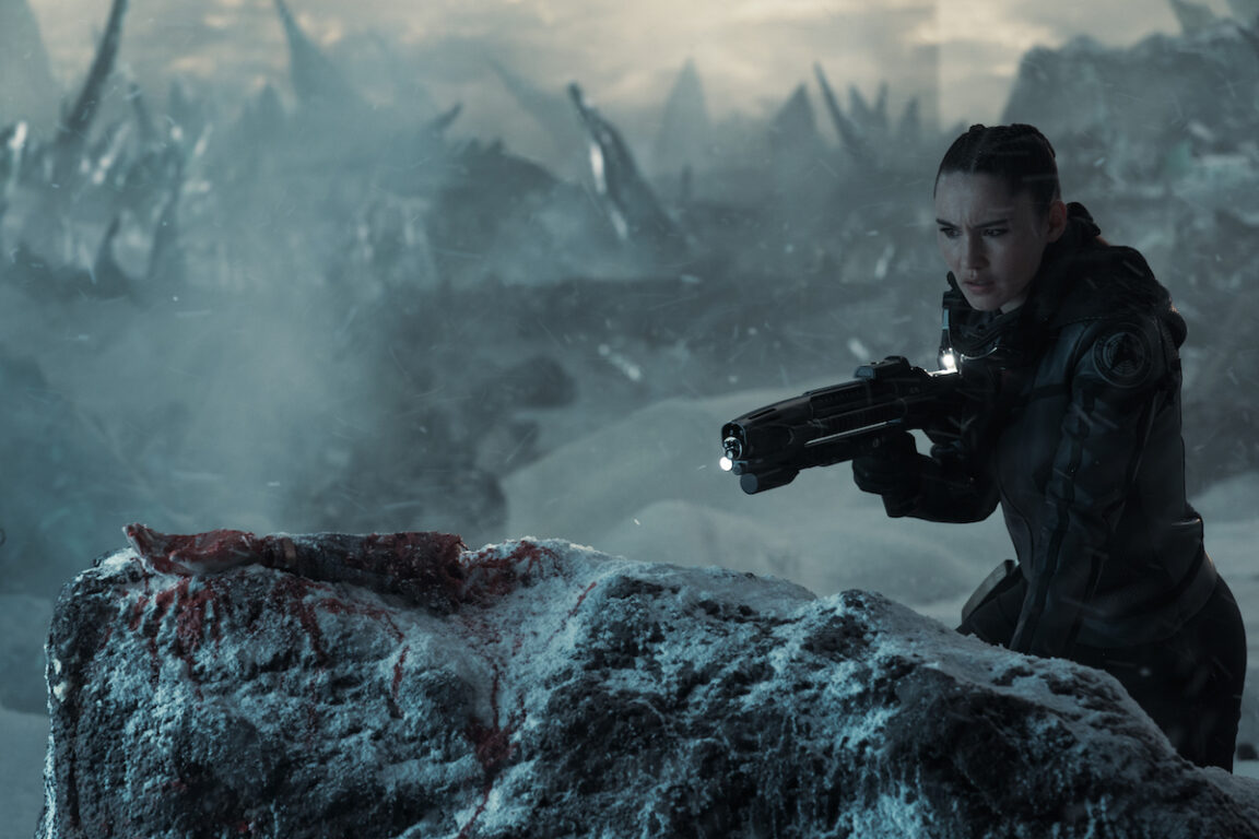Christina Chong as La'an of the Paramount+ original series STAR TREK: STRANGE NEW WORLDS. She is dressed in an EV Suit (without a helmet) and carrying a phaser rifle. On a frozen snowy planet, she discovers a bloody amputated arm.