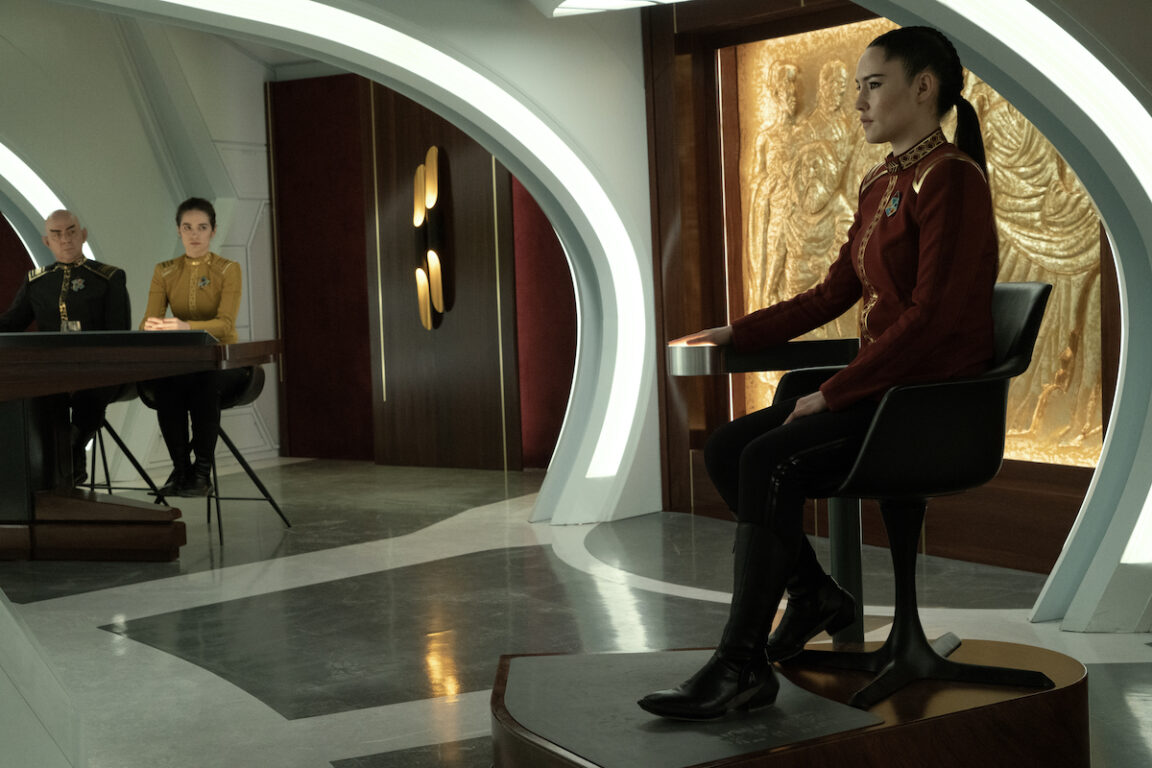 Melanie Scrofano as Batel and Christina Chong as La’an in episode 202 “Ad Astra per Aspera” of Star Trek: Strange New Worlds. La'An is in her formal uniform and on the courtroom stand. Batel looks on from the Prosecution's table.
