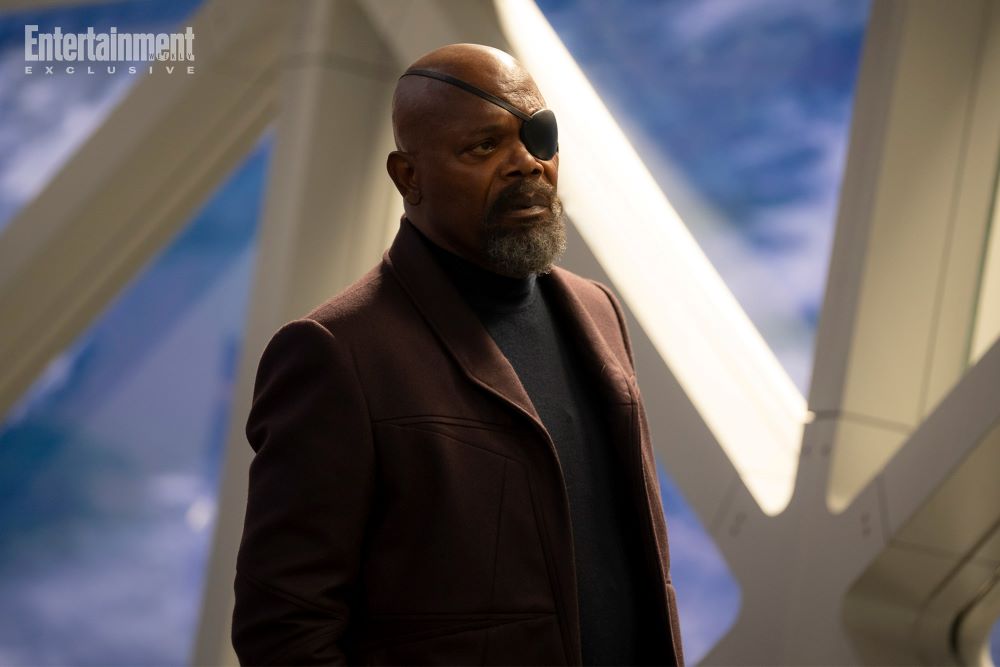 Nick Fury stands in the S.A.B.E.R. Space Station while wearing his signature eye patch and a burgundy coat. 