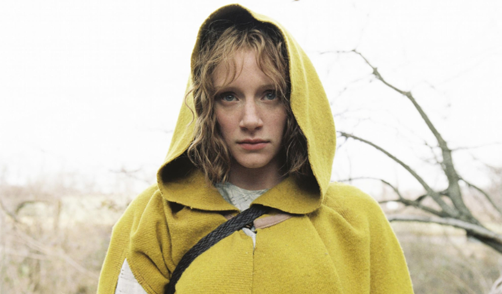 Bryce Dallas Howard wears a yellow cloak and stares forward in The Village. 
