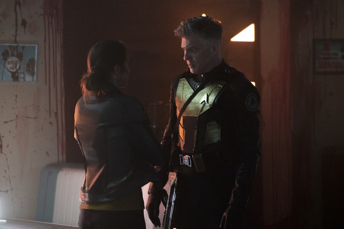 Melanie Scrofano as Batel and Anson Mount as Capt. Pike in Star Trek: Strange New Worlds. They are standing in the diner and looking at each other.