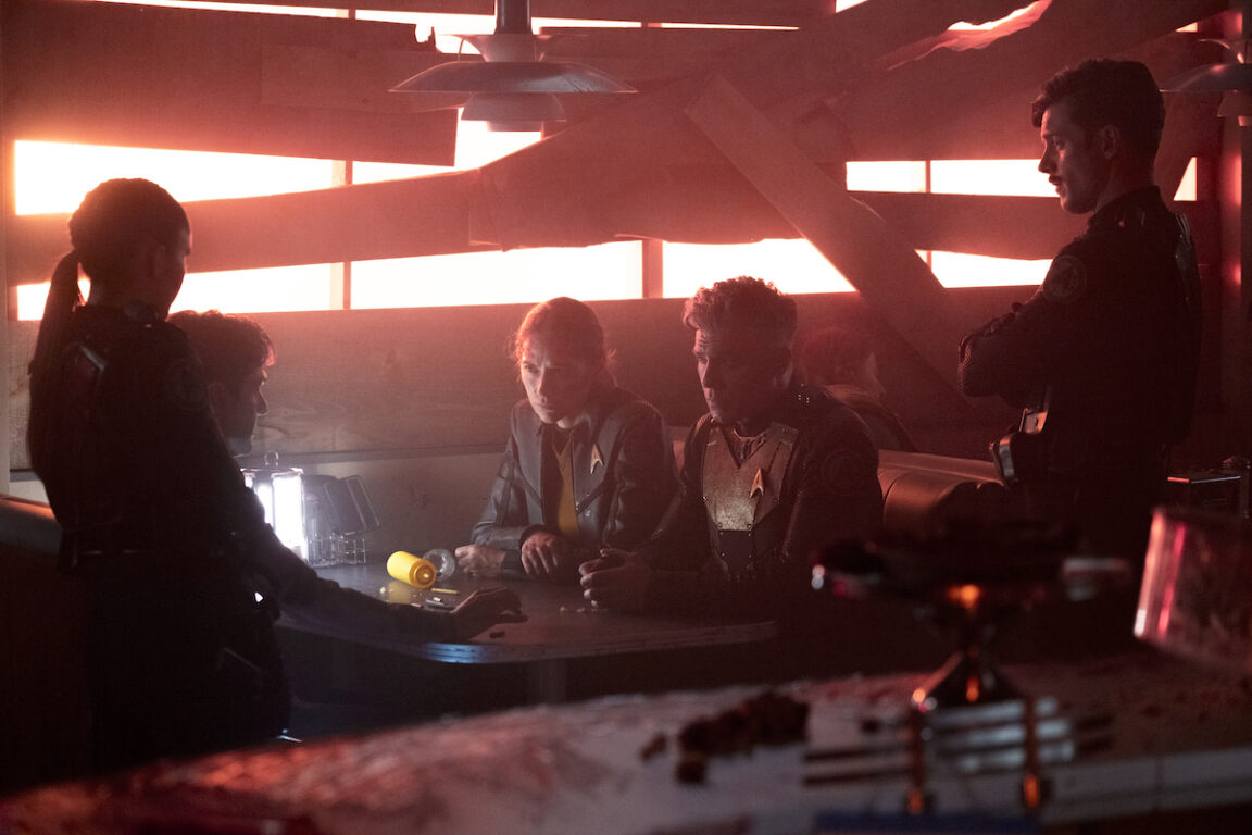 Melanie Scrofano as Batel, Anson Mount as Capt. Pike and Dan Jeannotte as Sam Kirk in Star Trek: Strange New Worlds' season finale. They are gathered around a table in the heavily damaged diner.