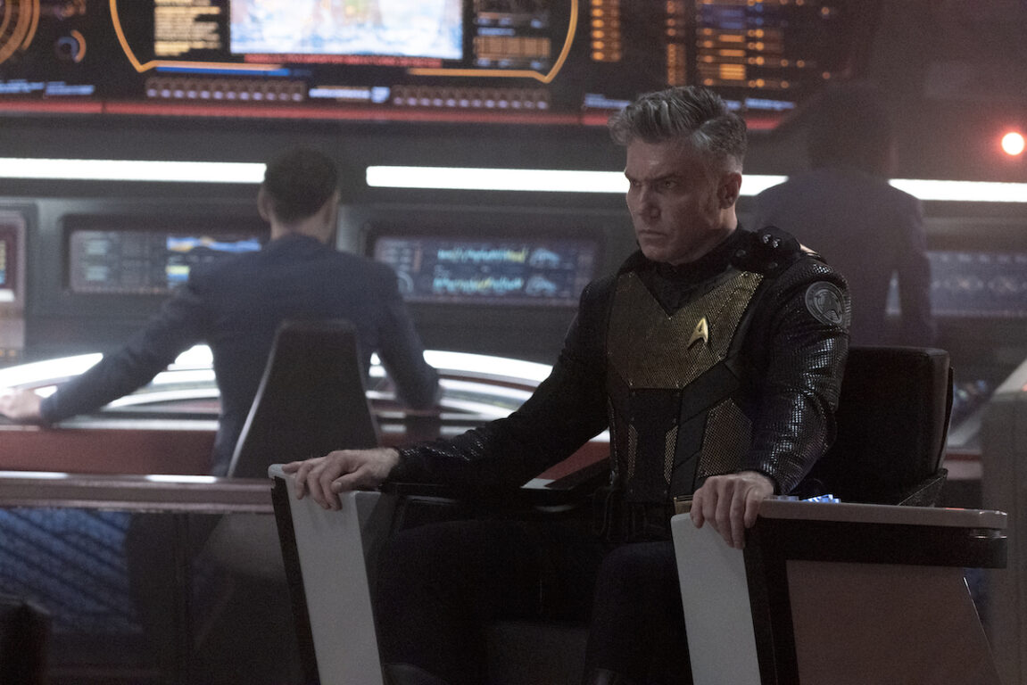 Ethan Peck as Spock and Anson Mount as Capt. Pike in the Star Trek: Strange New Worlds season 2 finale, "Hegemony." He's seated in his chair and wearing his special anti-gorn outfit.